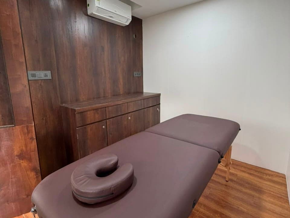 A massage room with the table set up beside its wood-panelled wall
